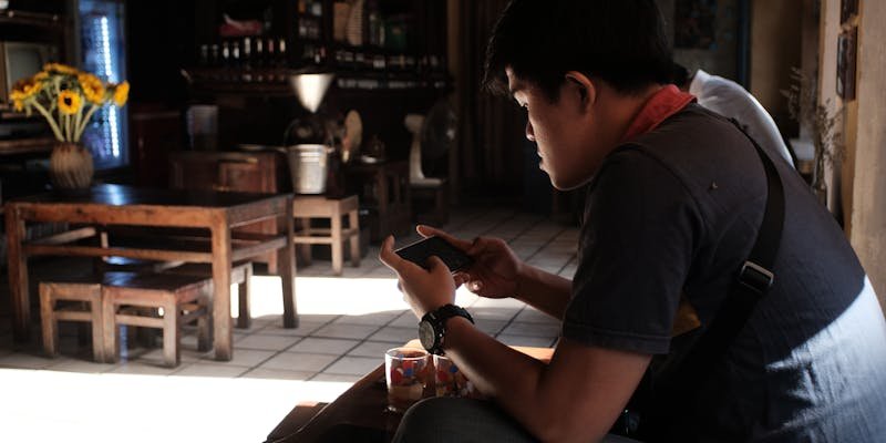 Homem em café usando smartphone com consciência digital