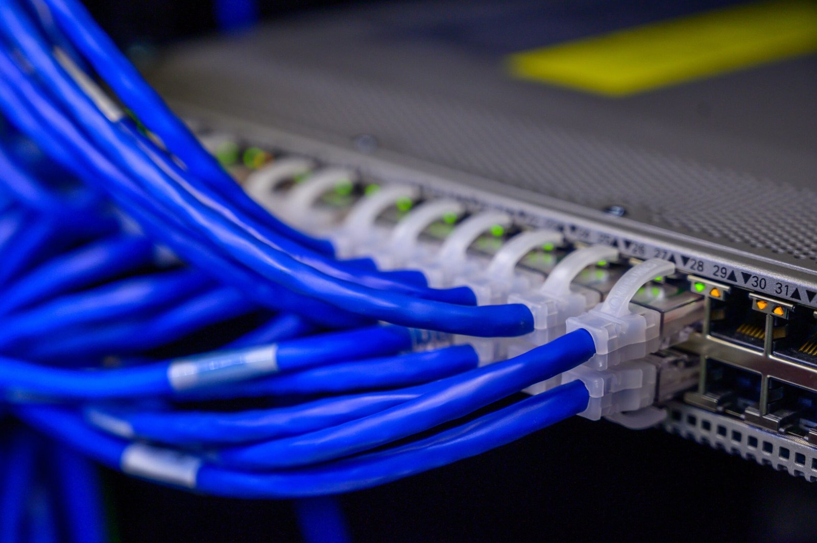 Cabos de rede azuis conectados em switch de data center representando sistemas distribuídos