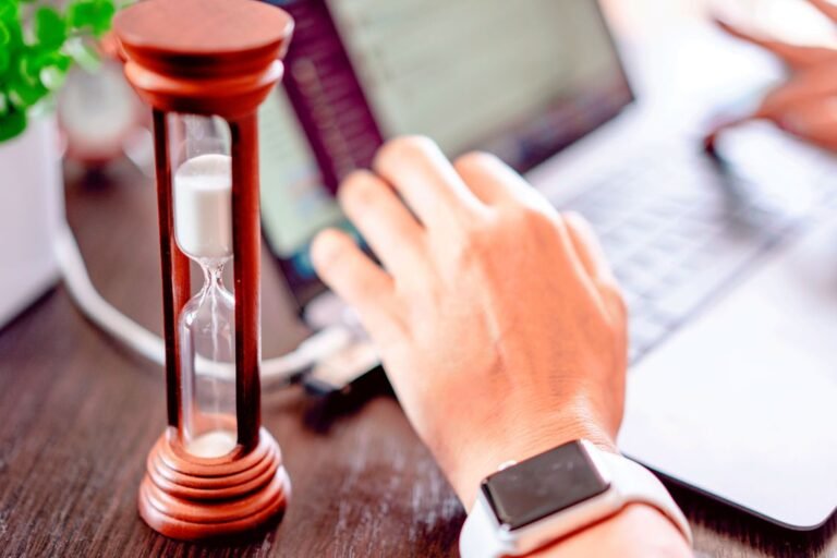 Pomodoro adaptativo em Python puro: mão em laptop com ampulheta representando ciclos de foco dinâmicos e gestão de tempo automatizada