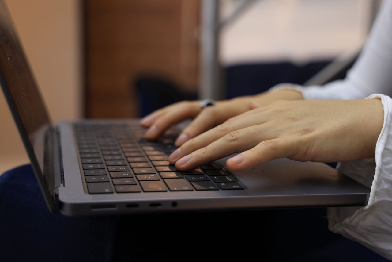 Mãos digitando no teclado durante revisão de texto com IA