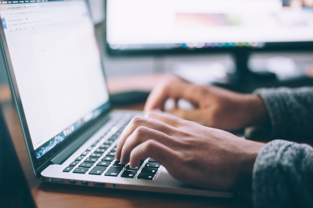 Mãos digitando em um laptop em ambiente de trabalho acolhedor
