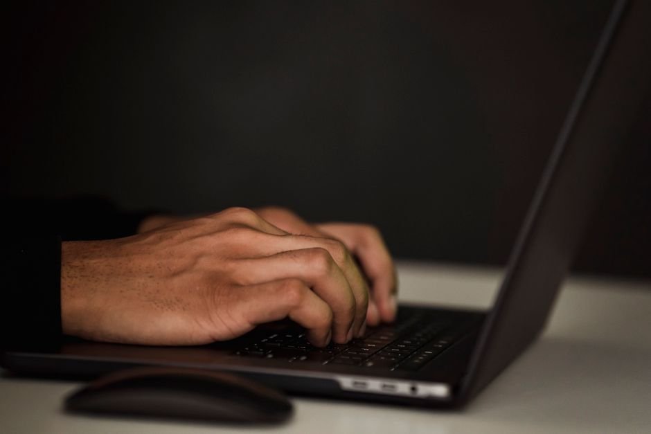 Pessoa trabalhando no laptop com uma xícara de café em ambiente moderno