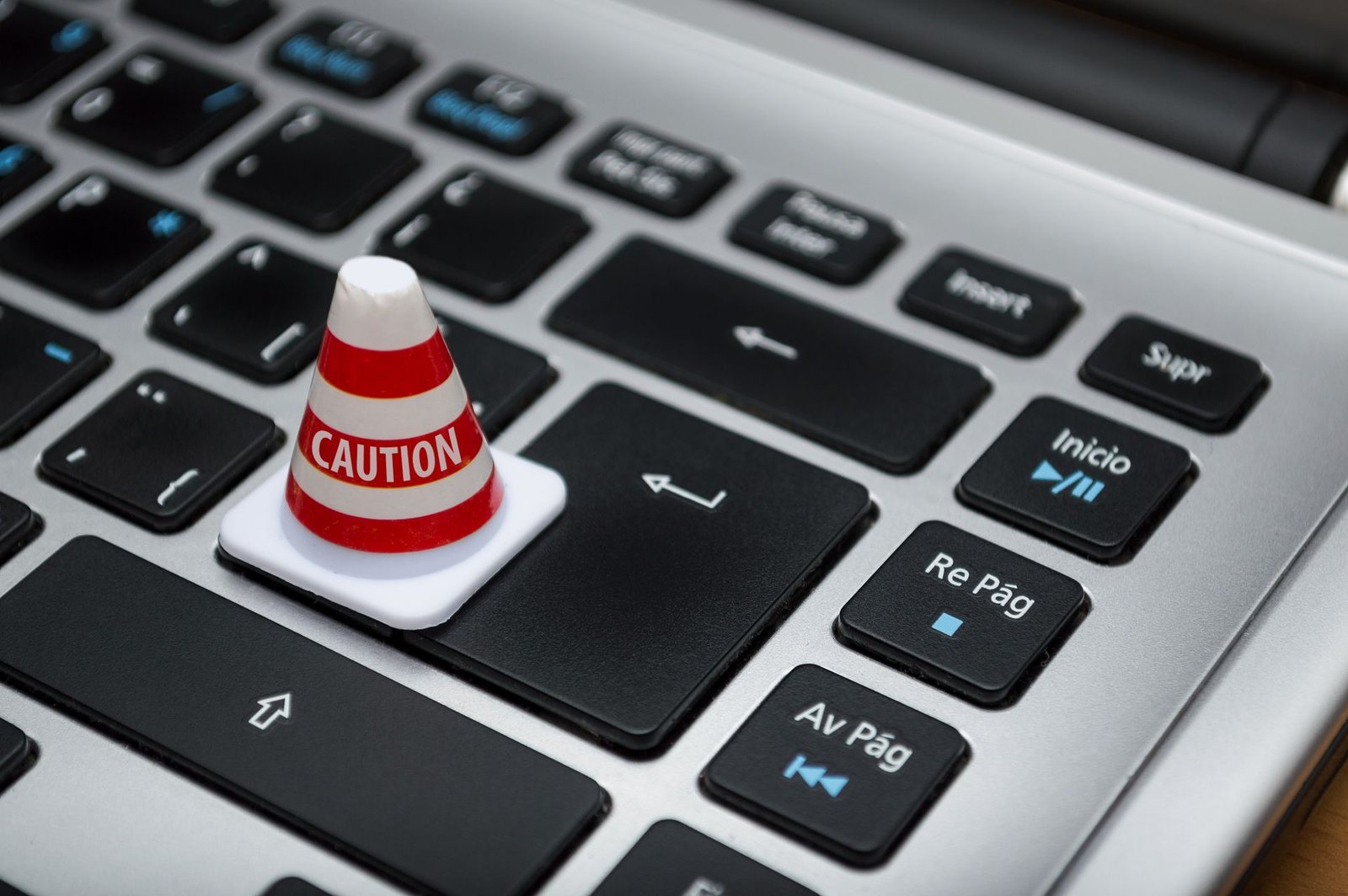 Cone de cautela sobre teclado de computador simbolizando alerta sobre erros de IA