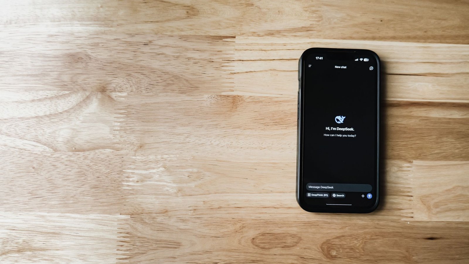 Smartphone exibindo interface de chatbot de IA sobre mesa de madeira