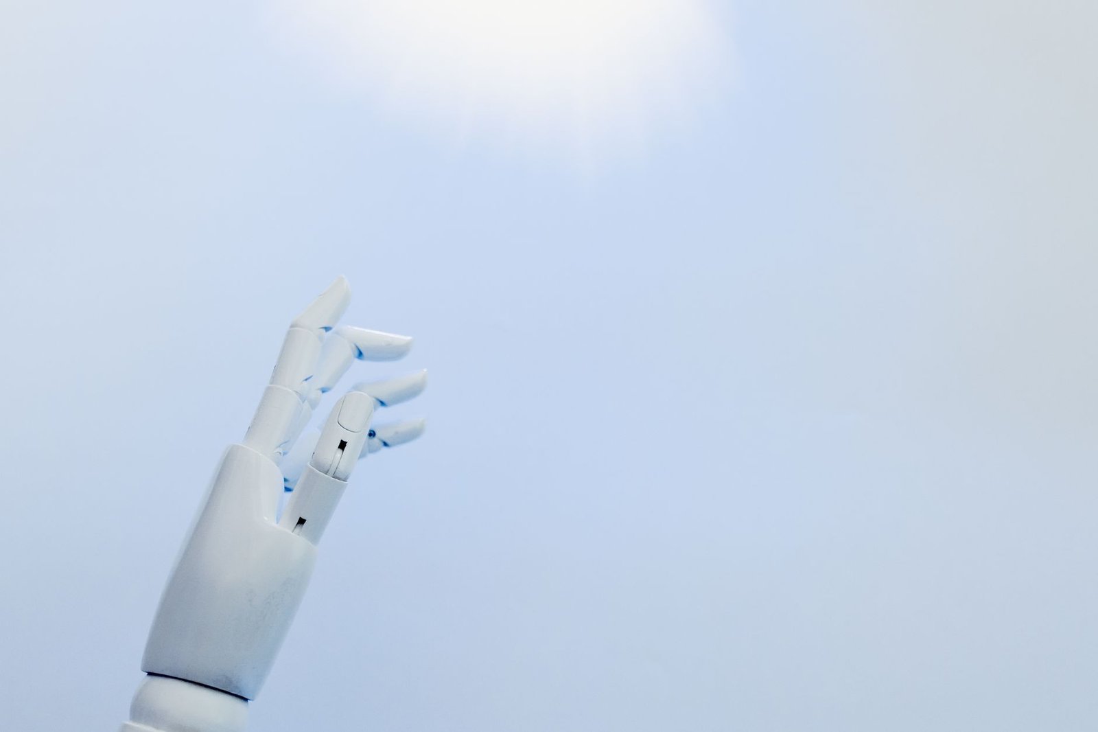 Mão robótica branca estendida em direção a uma luz brilhante simbolizando inovação