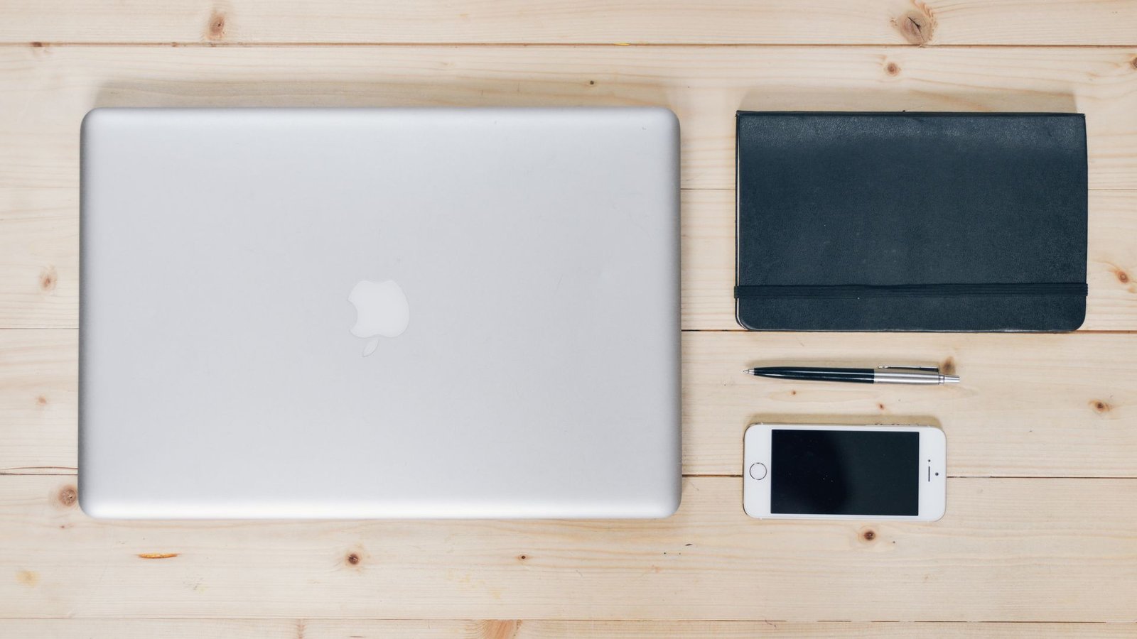 Mesa organizada com laptop, smartphone e caderno